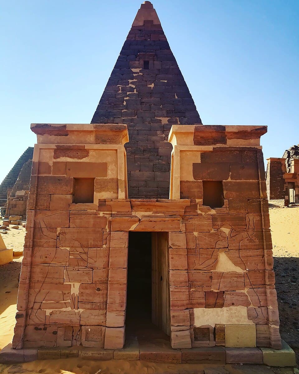 The eastern chapel of a Meroitic pyramid, its sandstone façade carved with reliefs and fronted by a small offering chamber — the customary approach to the tomb behind. Structures like this once stood before every royal pyramid at Meroë, serving as the ritual gateway between the living and the dead.
